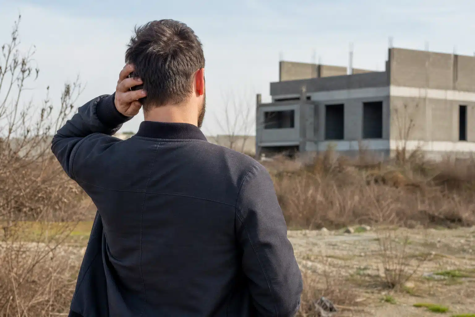 Homme vu de dos regardant maison en construction